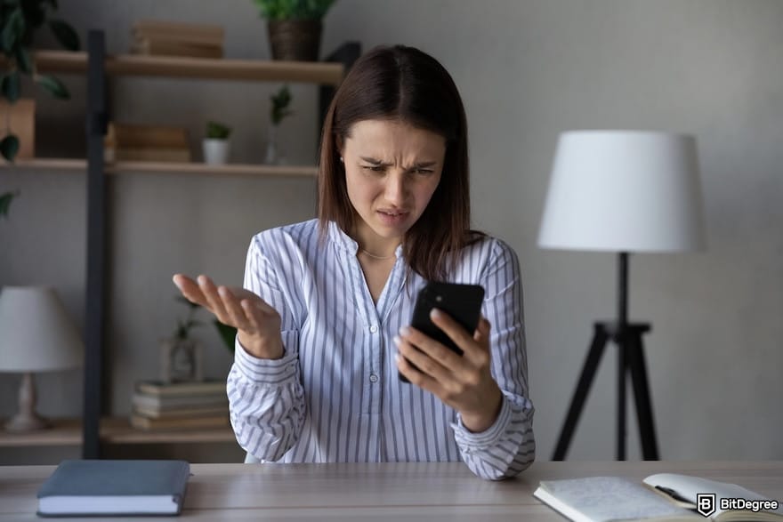 Payoneer alternative: an unhappy woman looking at her phone.