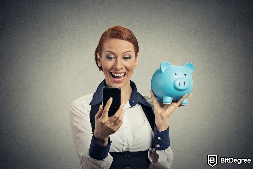 Polkadot staking: happy young woman holding piggy bank looking at smart phone.