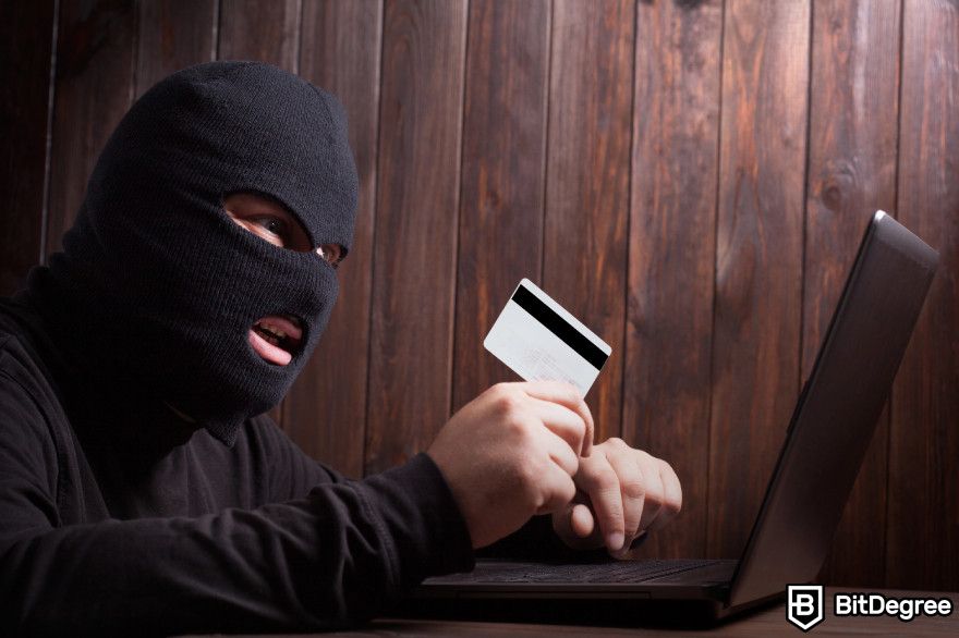 Polygon staking: a masked man holds a credit card in front of laptop.