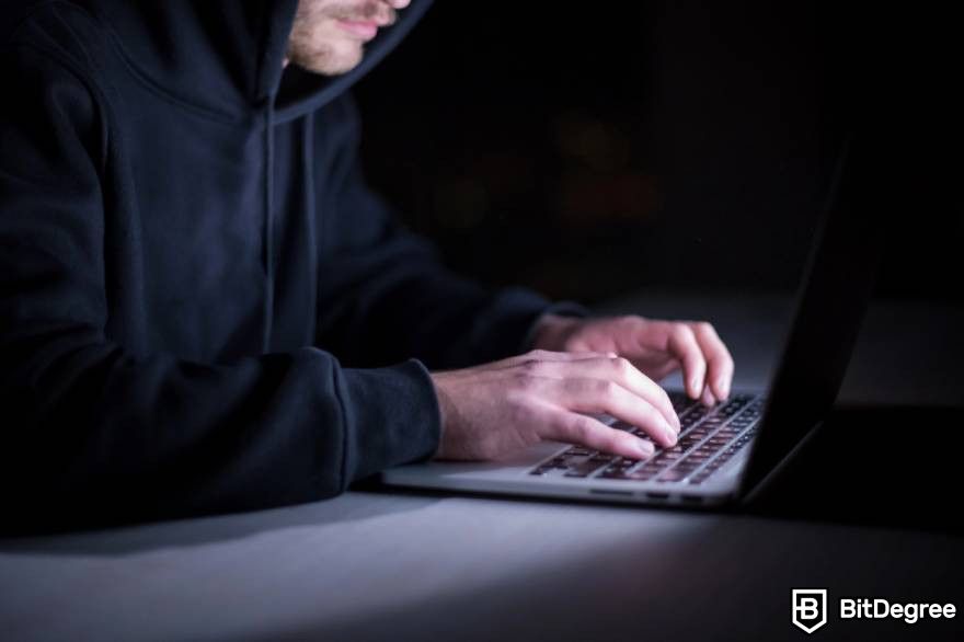 Pump and dump crypto: A man in a hoodie is engaged in typing on a laptop