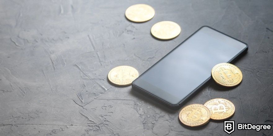 Revolut Crypto Review: Bitcoins next to a phone on a table.