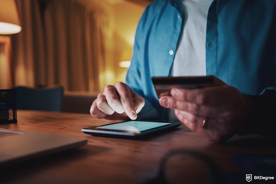 Safest way to send money: a man making transaction using a phone while holding his card.