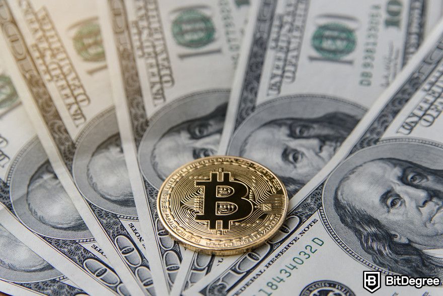 Should I buy Bitcoin: A Bitcoin token on top of hundred dollar bills.