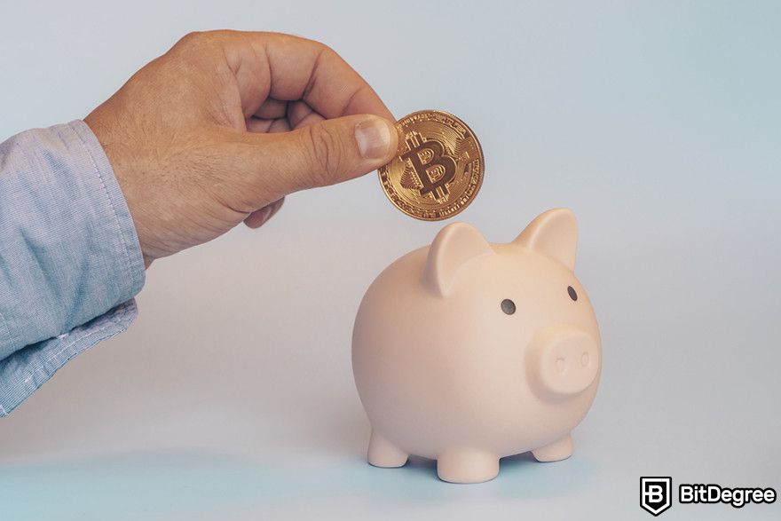 Staking crypto: A person putting a Bitcoin token into a piggybank.