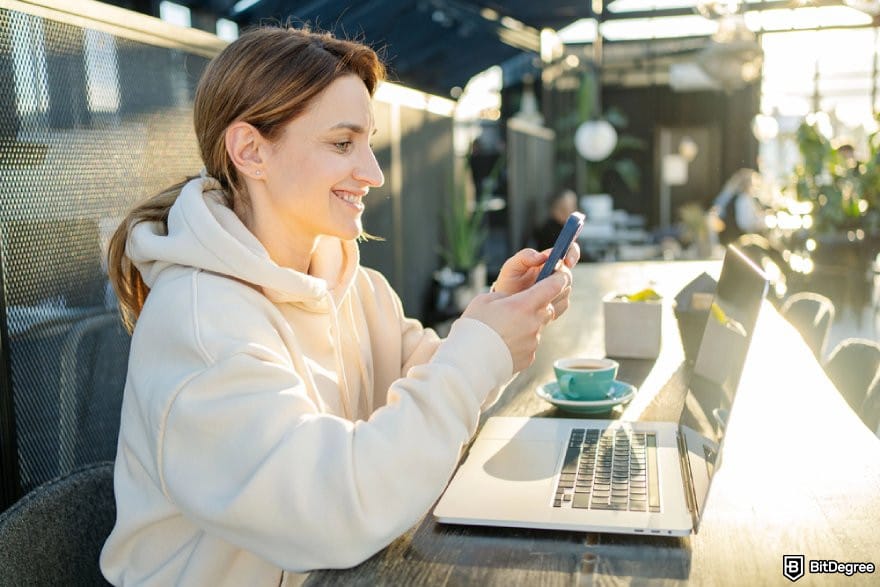 Uphold review: a person using a phone while smiling.