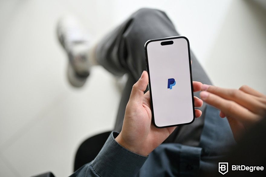 Virtual currency: A man holding a smartphone displaying Paypal.