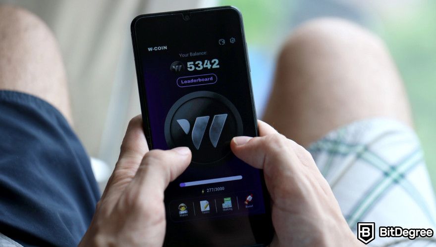 W-Coin Crypto: a man playing W-Coin on his phone.