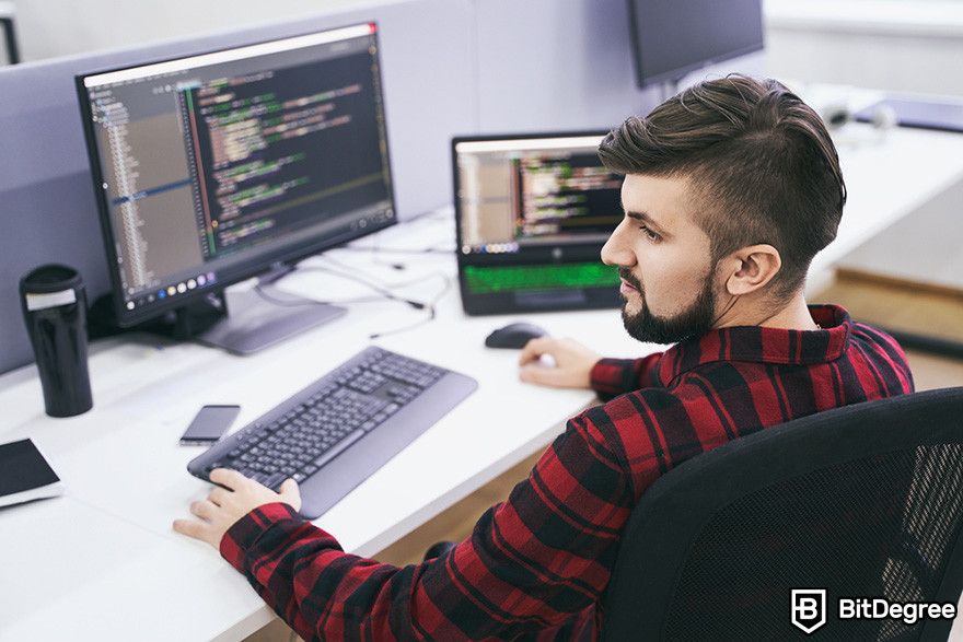 Web3 jobs: a person working on lines of code on a desktop computer and a laptop.