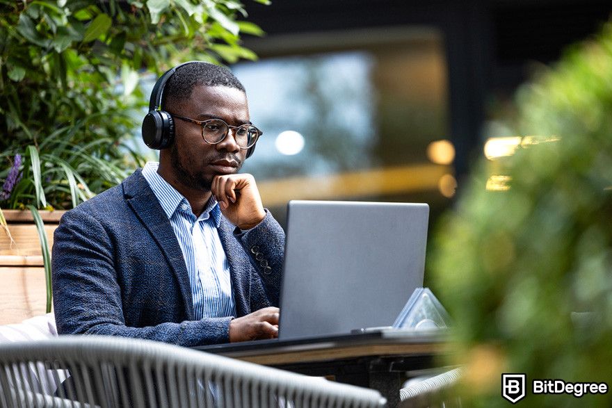 What is Bybit: a person using a laptop while wearing wireless headphones.