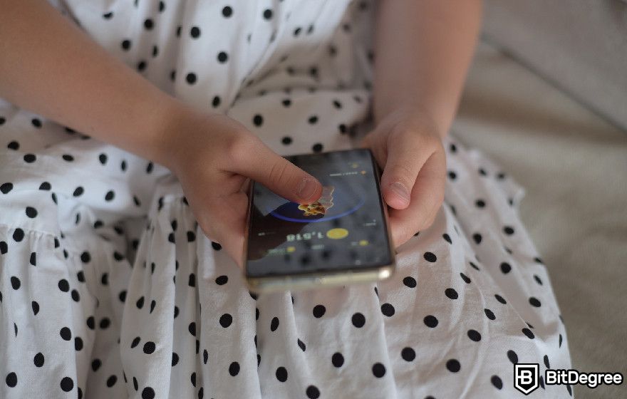 What is Hamster Kombat: a woman playing Hamster Kombat on the phone.