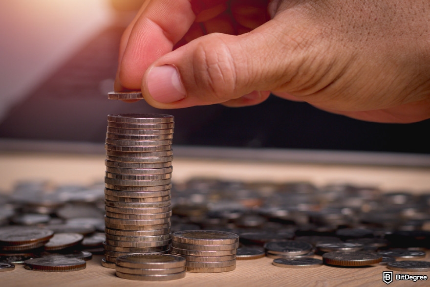 What is Pi Network: close-up of a hand stacking coins into a tall pile, symbolizing Pi coin potential use case for saving assets.