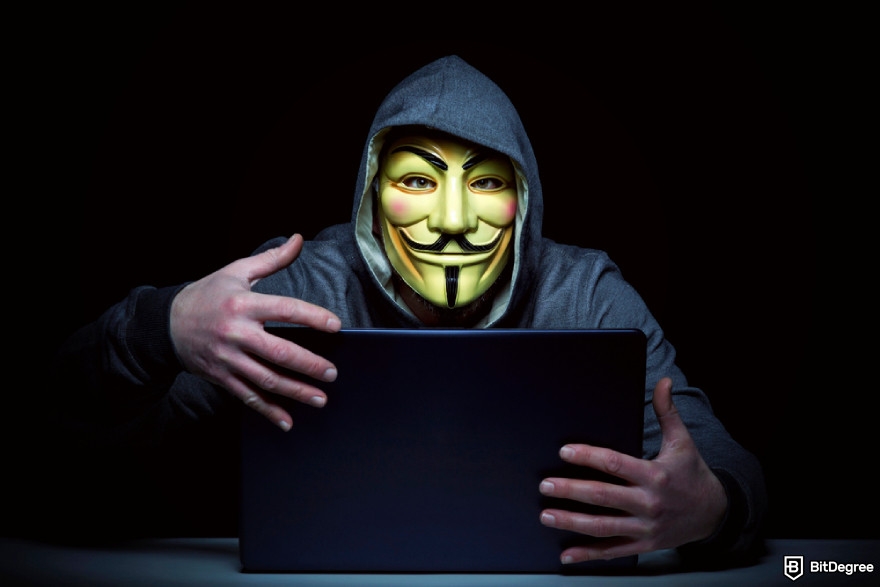 What is Pi Network: a person wearing a mask and a hoodie, sitting in a dark environment while using a laptop.