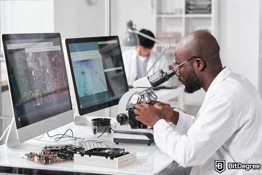 What is Render crypto: a scientist using a microscope in front of two desktop monitors.