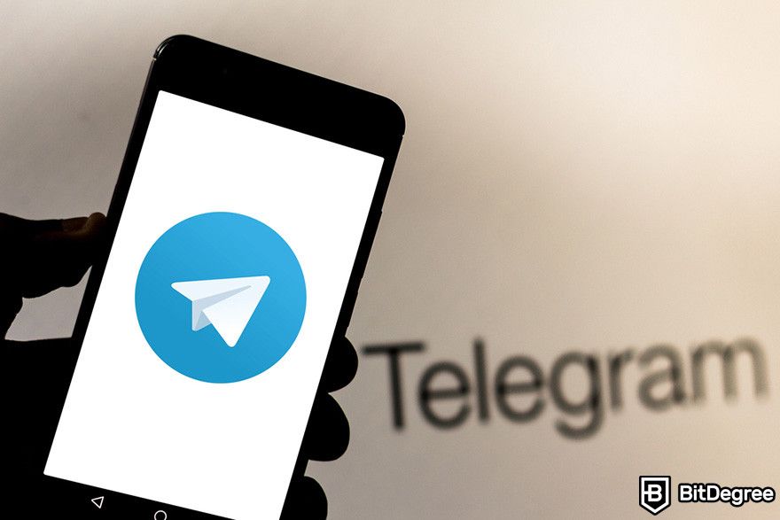 Toncoin là gì: một người cầm điện thoại thông minh có logo Telegram trên màn hình.