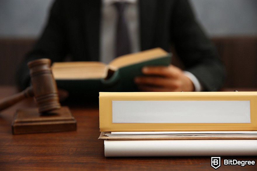 What is Worldcoin: a person reading a book in front of a gavel and a pile of documents.