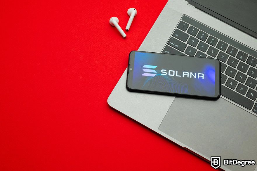 Where to buy BOOK OF MEME coin: a pair of wireless earphones, a laptop, and a mobile phone displaying Solana's logo on a red surface.