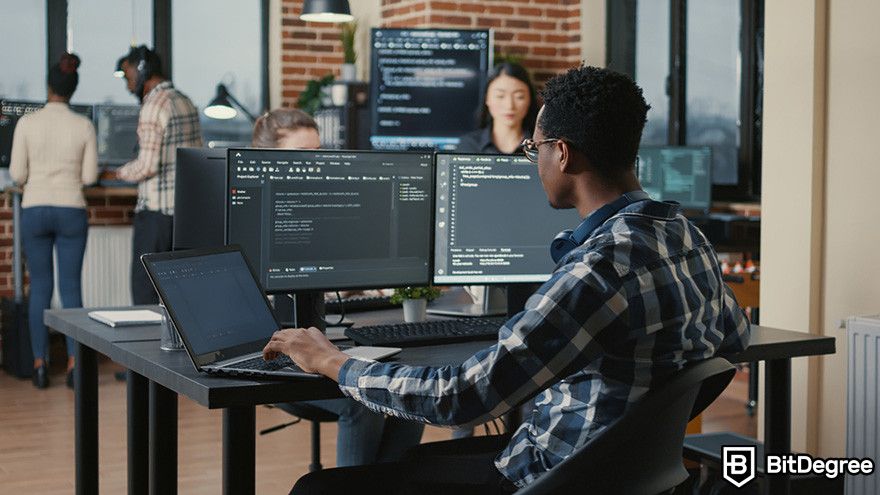 Why does crypto have value: a software developer working on code with multiple monitors in an office.