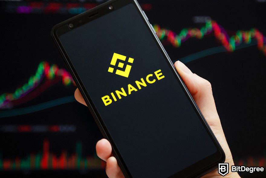 Why is crypto down: a person holding a mobile phone displaying the logo of Binance.