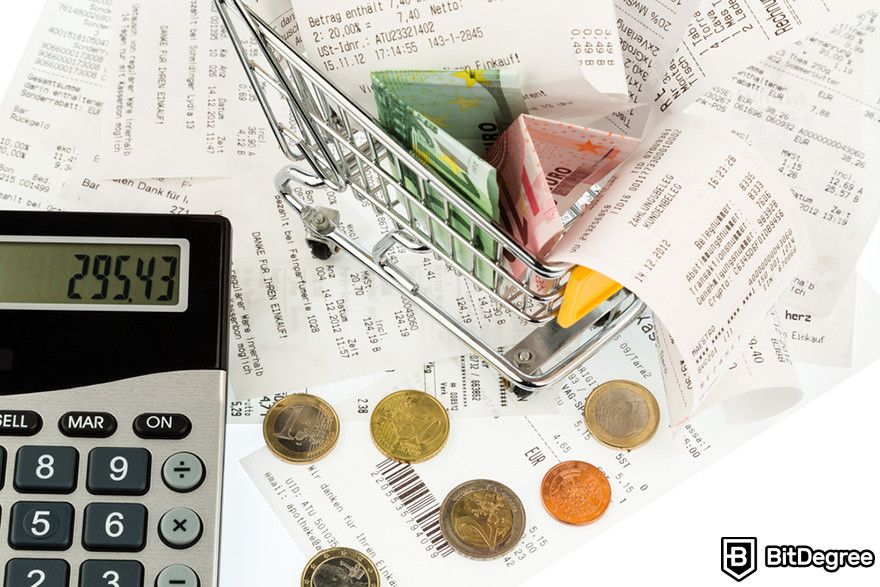 Why is crypto down: a mini shopping cart overflowing with receipts, coins, and a calculator on a white background.