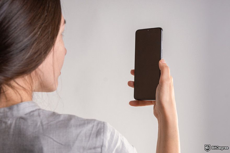 Withdrawal Bitstamp: a person holding a phone in front of their face.