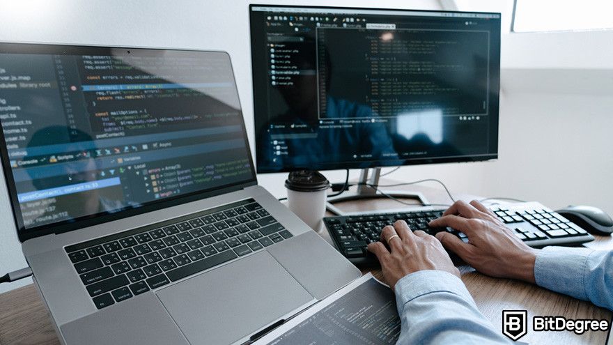 Zero knowledge proof: a person working on programming codes on a desktop computer and a laptop.