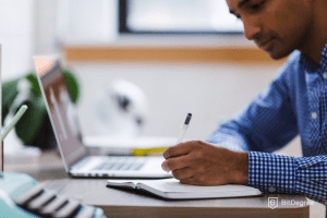 Tipos de Bases de Datos: Hombre escribiendo en su cuaderno.