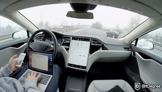 Udacity беспилотные автомобили: мужчина работает на ноутбуке в беспилотном автомобиле.