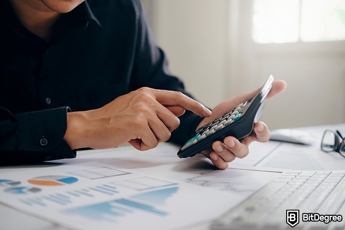 Best online finance degree programs: a man is holding a calculator.