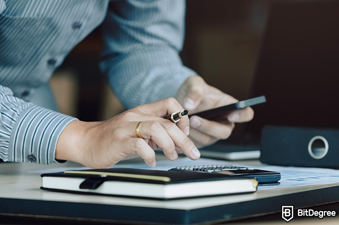 Best online finance degree programs: a man is checking calculations on his phone.