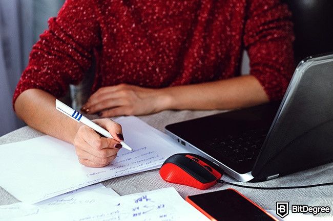 Distance Learning: woman taking notes next to her laptop.