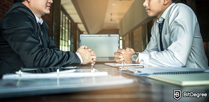 Harvard negotiation course: two businessmen sat at a table opposite each other.