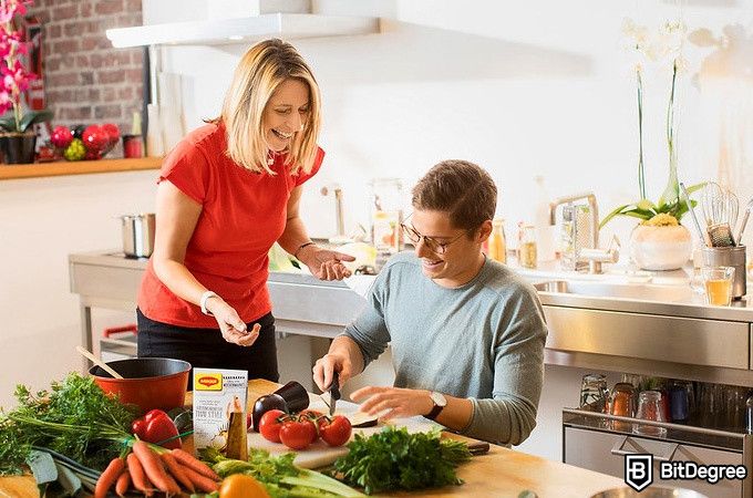 Học nấu ăn trực tuyến: người phụ nữ nhìn người đàn ông đang thái rau.