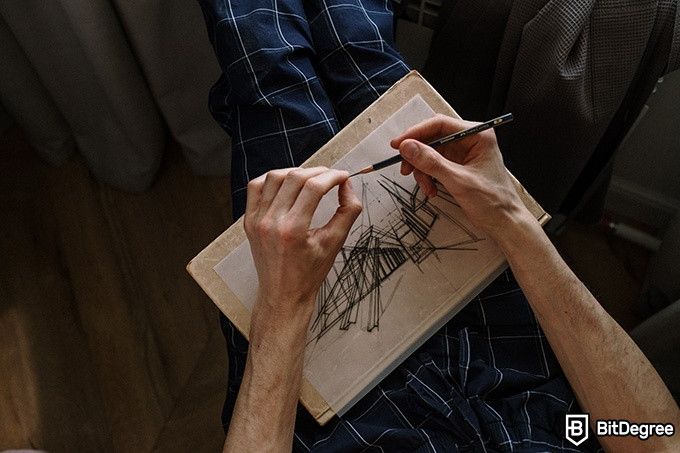 How to draw: a man is drawing with paper placed on his legs.