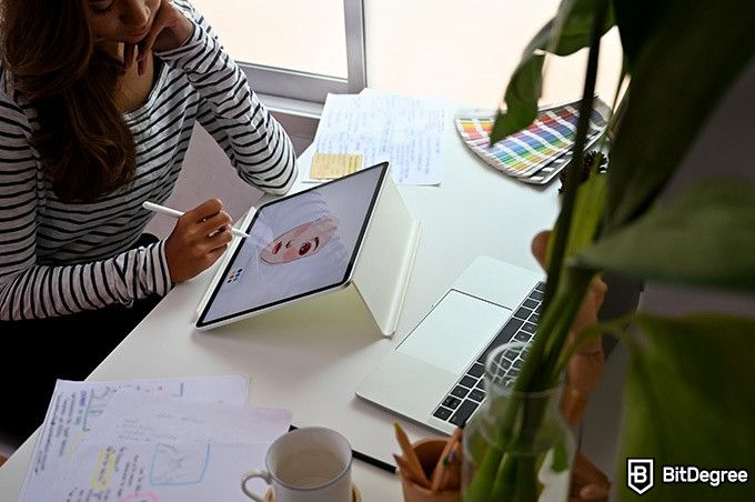 How to draw: a woman is drawing a face on a tablet screen.