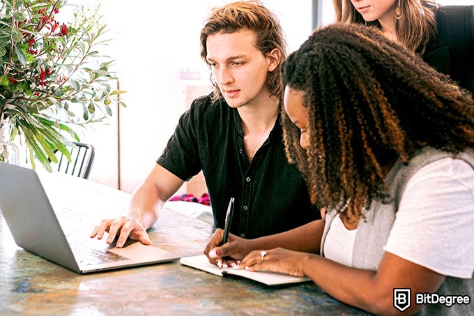 Hybrid Learning: a man and two women are looking at a laptop.