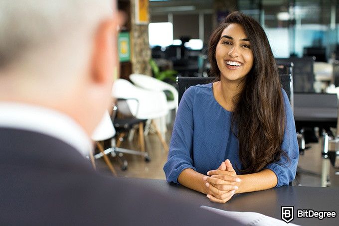 Python Udacity: seorang wanita tersenyum lebar ketika diwawancara.