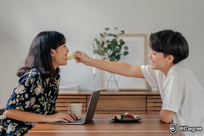 Nutrition courses online: one girl giving the other girl a slice of apple.