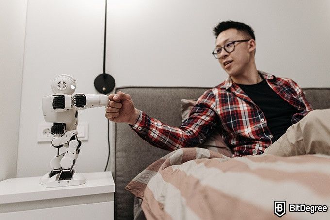 Online Artificial Intelligence Course: man fist-bumping a robot.
