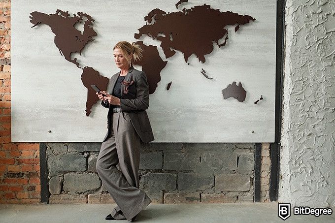 Online ethics courses: a woman stands in front of a wall with an atlas decoration.