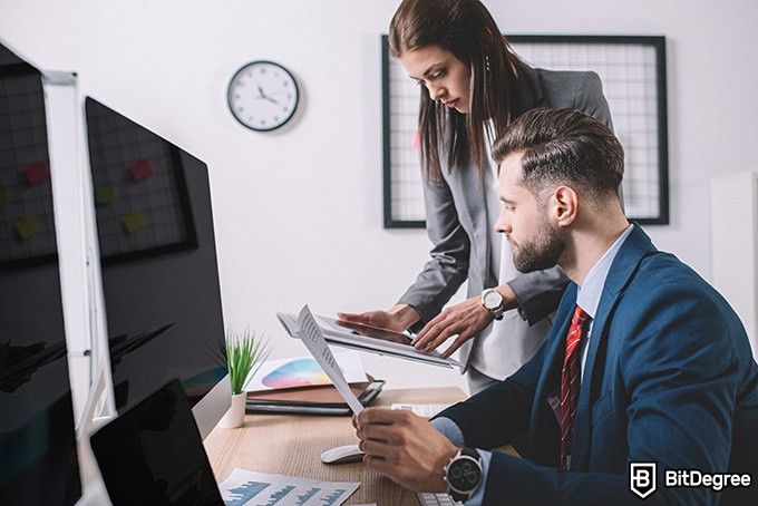 Online information technology degree: two corporate workers are looking at a tablet.