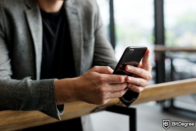 Online information technology degree: a man is typing on a phone.