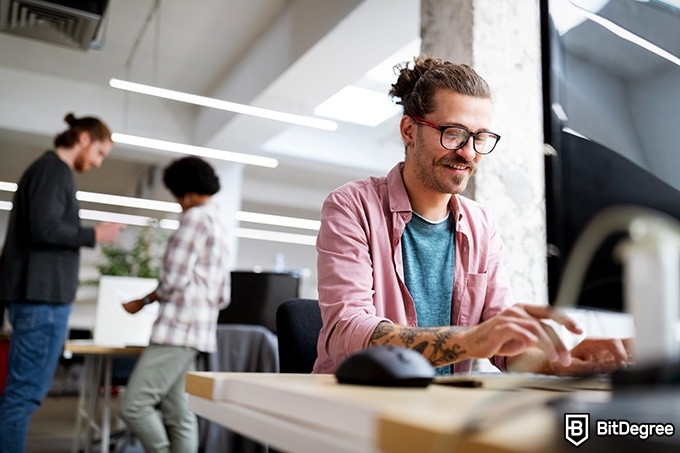 Online information technology degree: a man is smiling while typing on a computer.