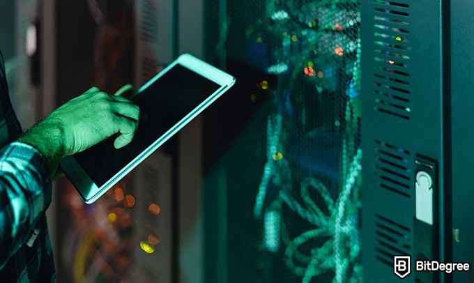 Online information technology degree: a person is checking the servers on a tablet.