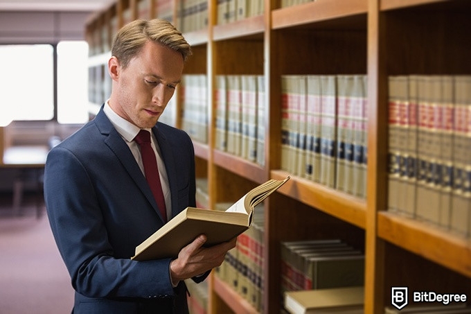 Online Law Courses: lawyer reading a book in the library.