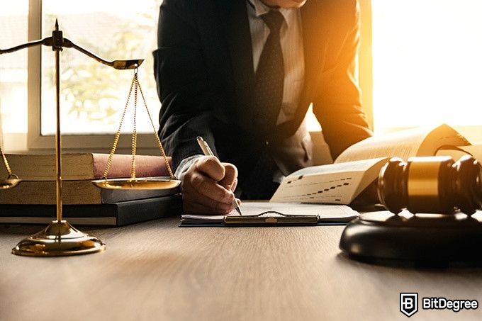 Online Law Courses: lawyer filling out paperwork at his desk.