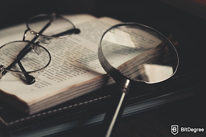 Online literature course: glasses and a magnifying glass on top of the book.