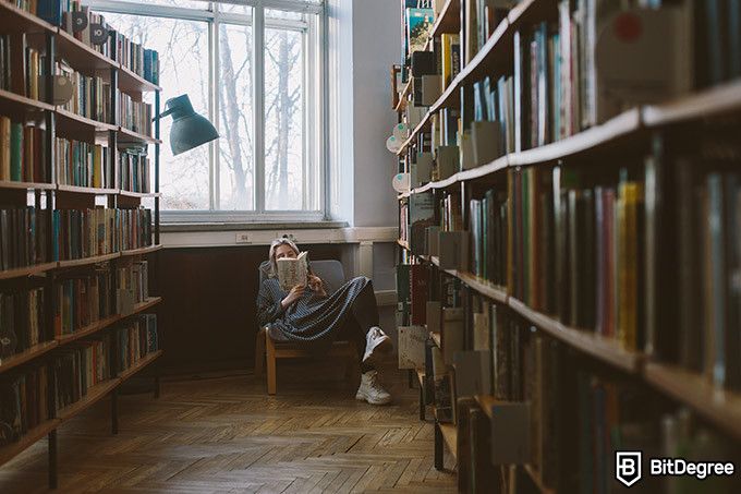 Online literature course: a woman reading in a library.