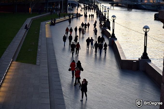 Online social sciences degree: a crowd of people walking by a riverside.