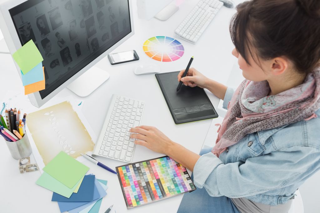 Os Melhores Cursos de Design Gráfico Online: Mulher desenhando em uma mesa digitalizadora na frente de um computador.