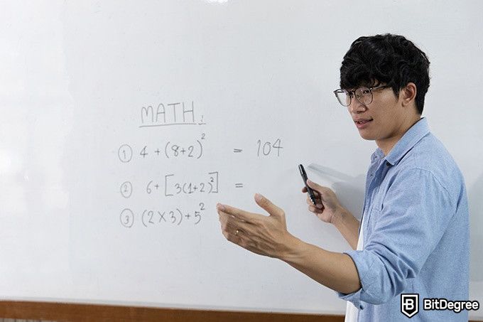Курсы алгебры: парень объясняет алгебру у доски.
